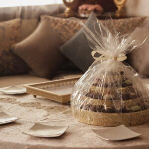 A beautifully wrapped gift tray of assorted sweets on an ornate table setting, perfect for celebrations.